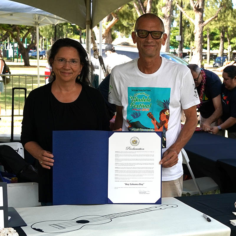 Ukulele Hall of Fame directors Nuni Walsh and Paul Syphers with the Governor's Proclamation designating July 27th, 2024 Roy Sakuma Day
